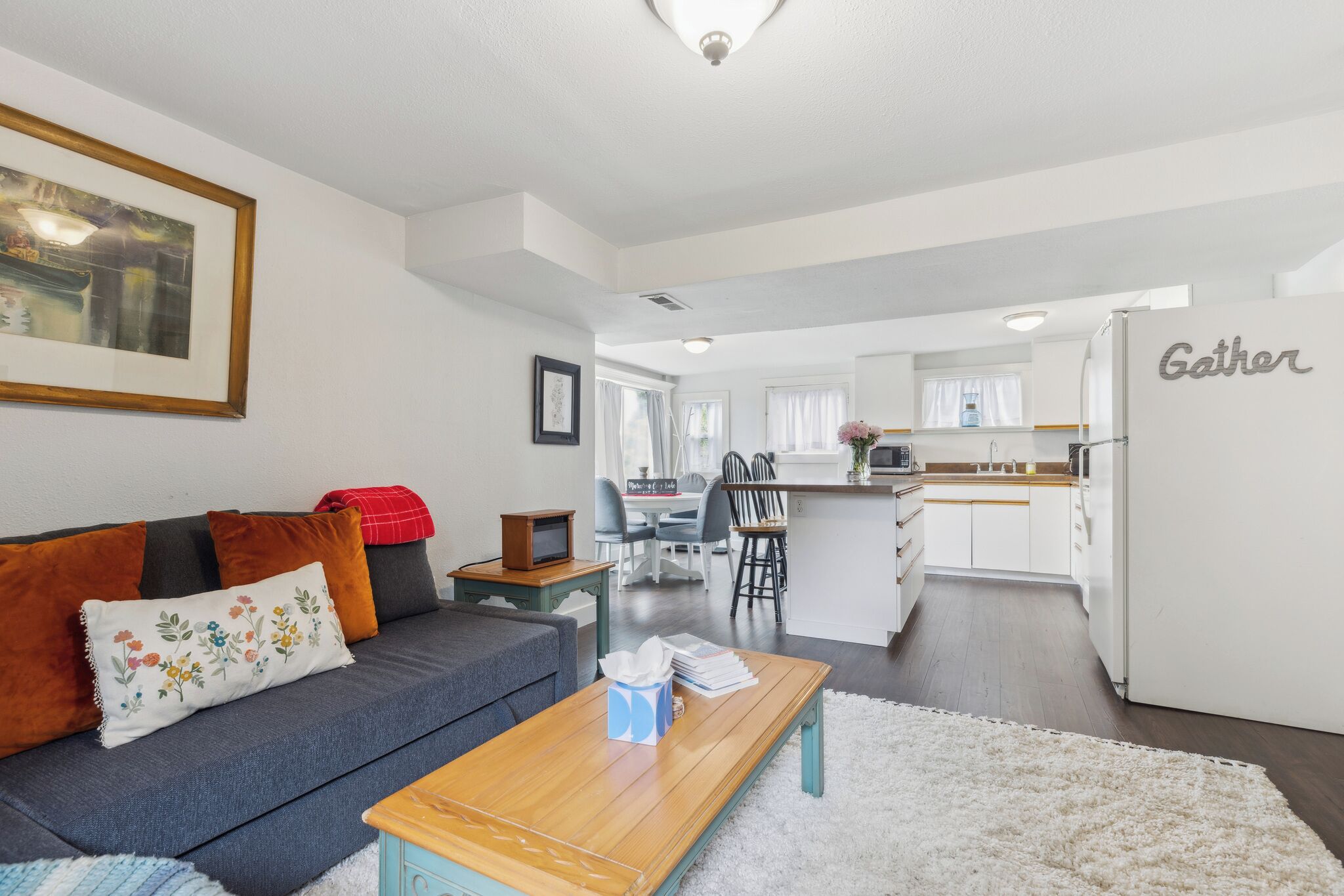 A modern living room with a sofa, coffee table, and a kitchen area in the background.