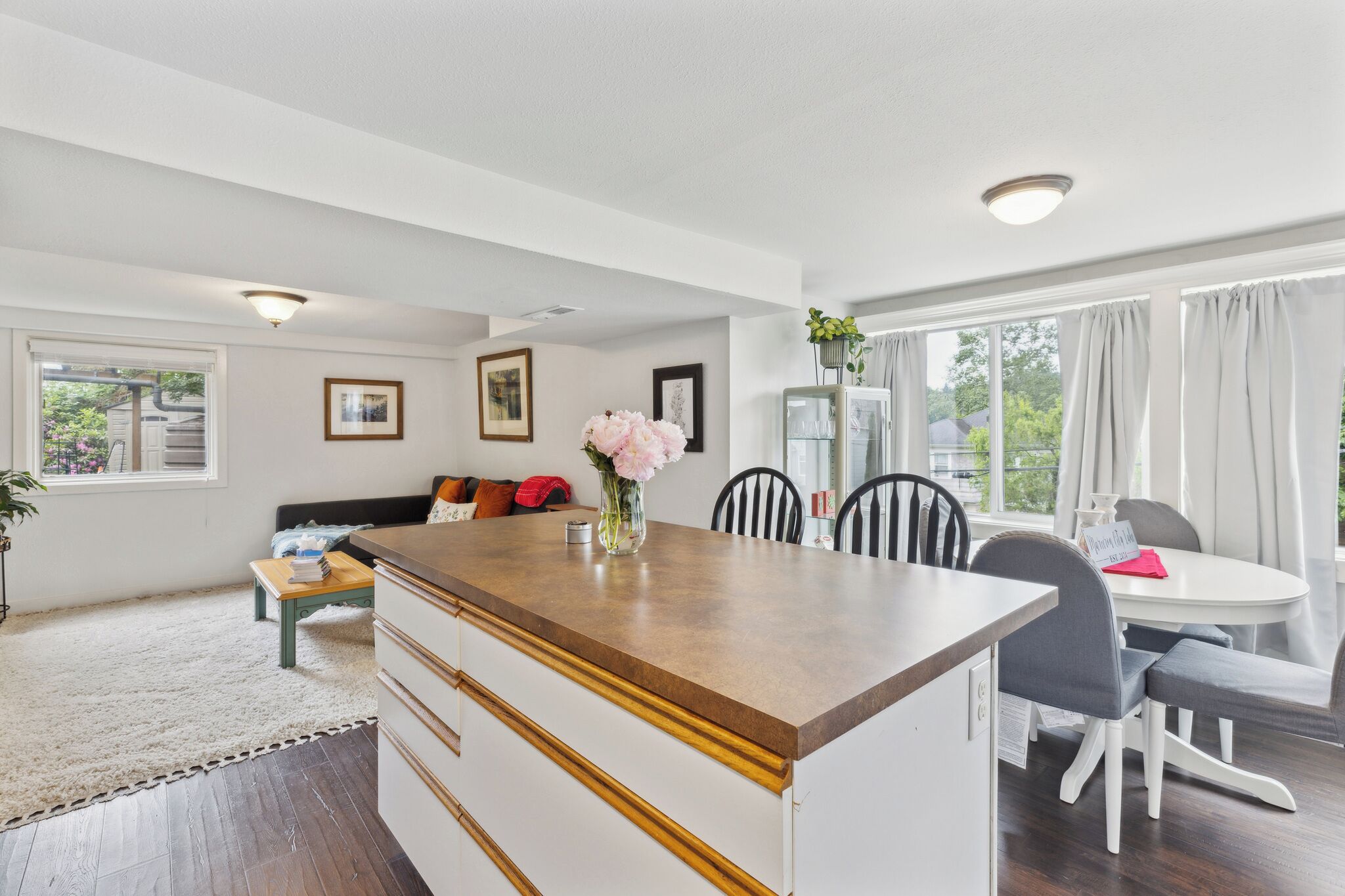 A modern kitchen with a central island, dining area with chairs, and a sofa.