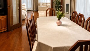 Un coin repas agrémenté d’un lustre, de chaises en bois, d’une table recouverte d’une nappe blanche et d’une plante servant de centre de table.