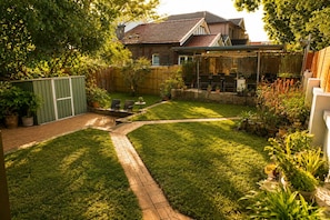 A backyard with a brick pathway, potted plants, and outdoor furniture.