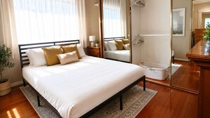 Une chambre à coucher bien rangée, avec un lit, des tables de chevet, un miroir et une plante.