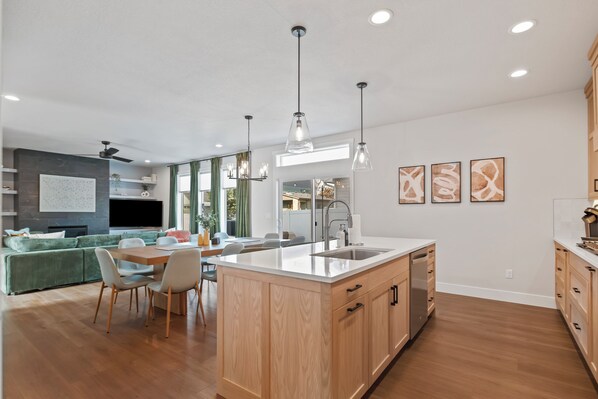 Une cuisine moderne dotée d’un îlot central, de meubles en bois et de luminaires suspendus.