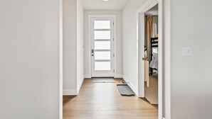 A hallway with a white door, a ceiling light fixture, and a doormat. - Pro Golf Simulator and Hot Tub, New Luxury 4 BR, Boise Home Sleeps 12 (Boise)