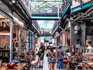 A narrow street with shops on both sides, people walking, and a variety of items for sale. - Zimmer mit Badezimmer by Interhome (Paris)