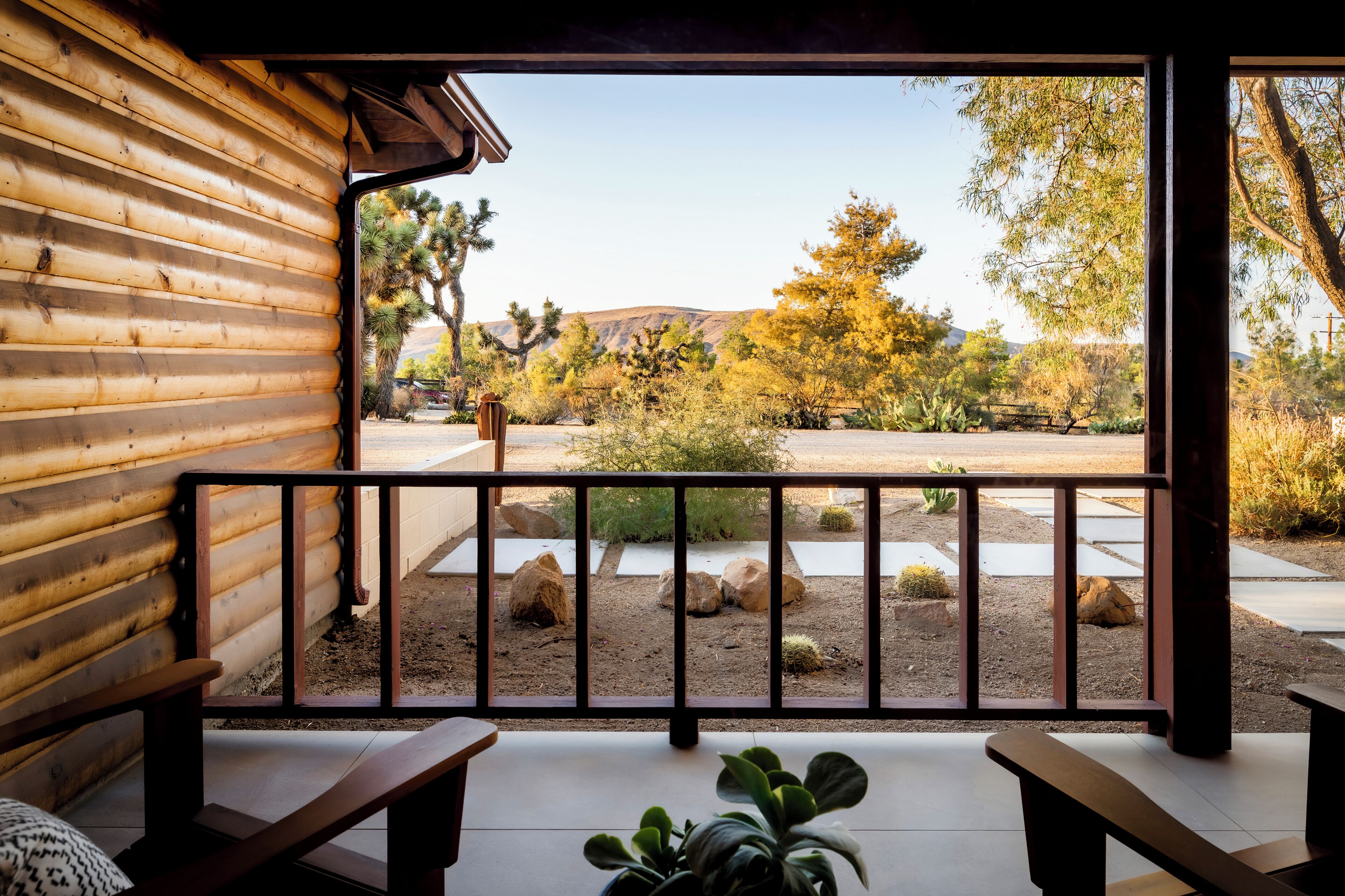 Une cabane en bois dotée d’un balcon donnant sur un paysage désertique parsemé de cactus et d’arbres.