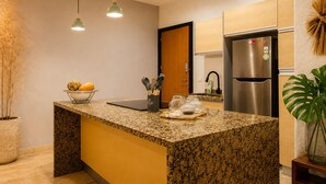 Una cocina moderna con encimera de granito, electrodomésticos de acero inoxidable e iluminación colgante.