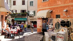 A narrow street with outdoor seating, a coffee stand, and a shop with colorful items. - Wohnung in Malcesine mit Privatstrand by Interhome (Malcesine)