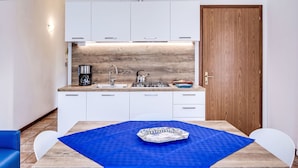 Una cocina moderna con armarios blancos, un protector contra salpicaduras de madera y un mantel azul.