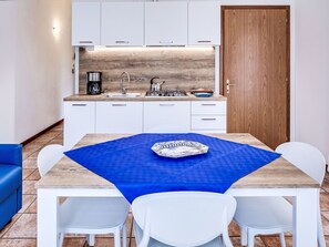 Eine moderne Küche mit weißen Schränken, einer Holzrückwand und einer blauen Tischdecke.