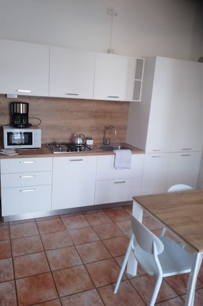 A compact kitchen with white cabinets, a microwave, a gas stove, and a sink. - Zwei-Zimmer-Wohnung mit Seeblick by Interhome (Malcesine)