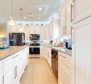 A modern kitchen with white cabinetry, stainless steel appliances, and granite countertops. - LCV33 Shared Pool, Private Hot Tub,Propane Grill (Port Aransas)