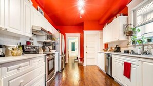 A kitchen with white cabinets, a wooden floor, and a red ceiling.