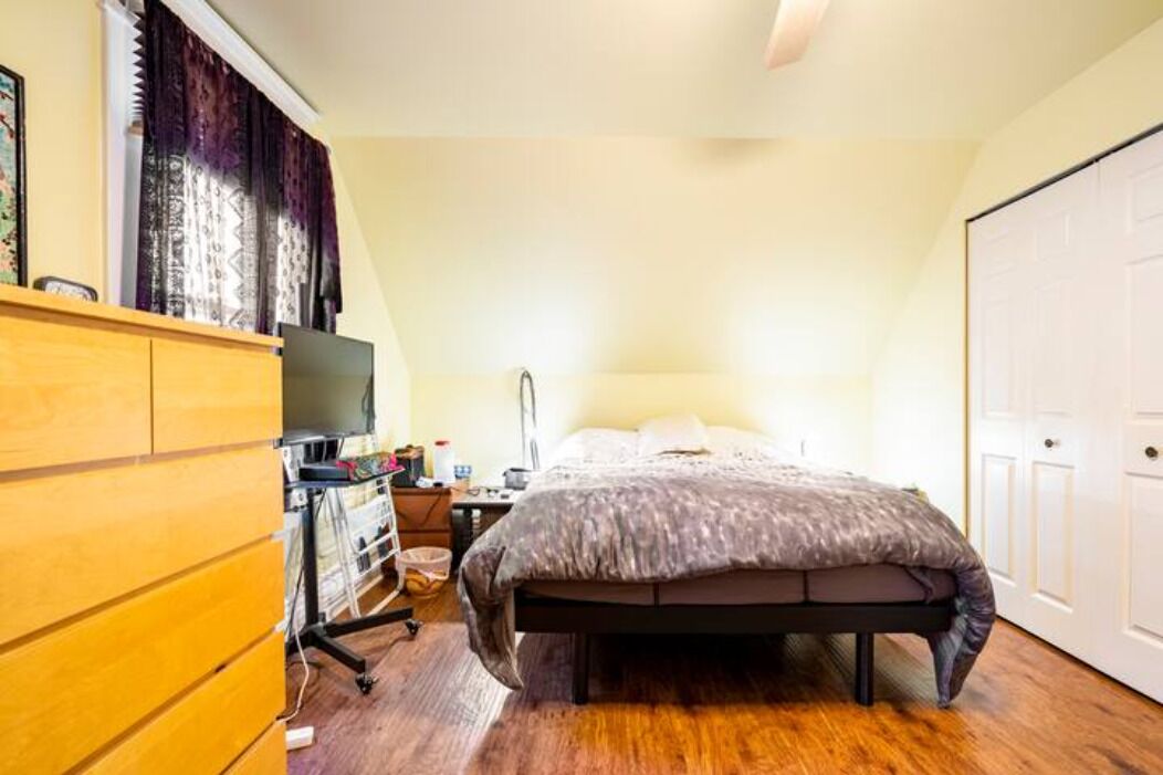 Une chambre à coucher comprenant un lit, une commode en bois, un téléviseur, un bureau et une armoire.