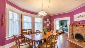 A dining room with a wooden table and chairs, a chandelier, and a fireplace.