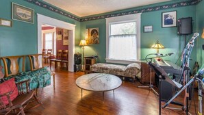 A room with a wooden floor, a sofa, a rocking chair, a table, and a window with curtains.