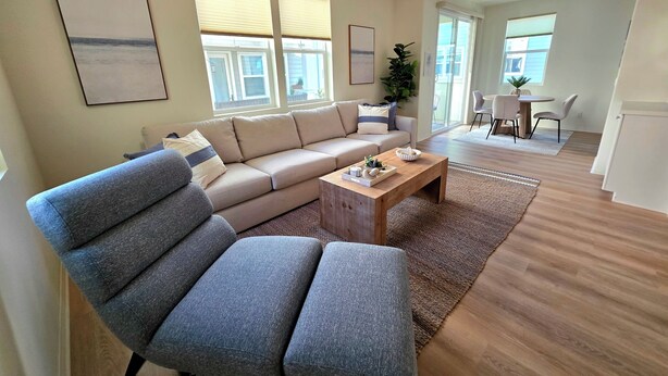 Uma sala moderna com sofá, mesa de centro e um espaço de jantar com cadeiras.