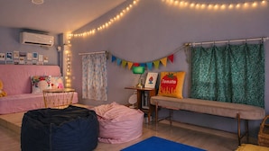 A cozy living room with a pink sofa, a bean bag, a blue rug, a small table, and a bench.