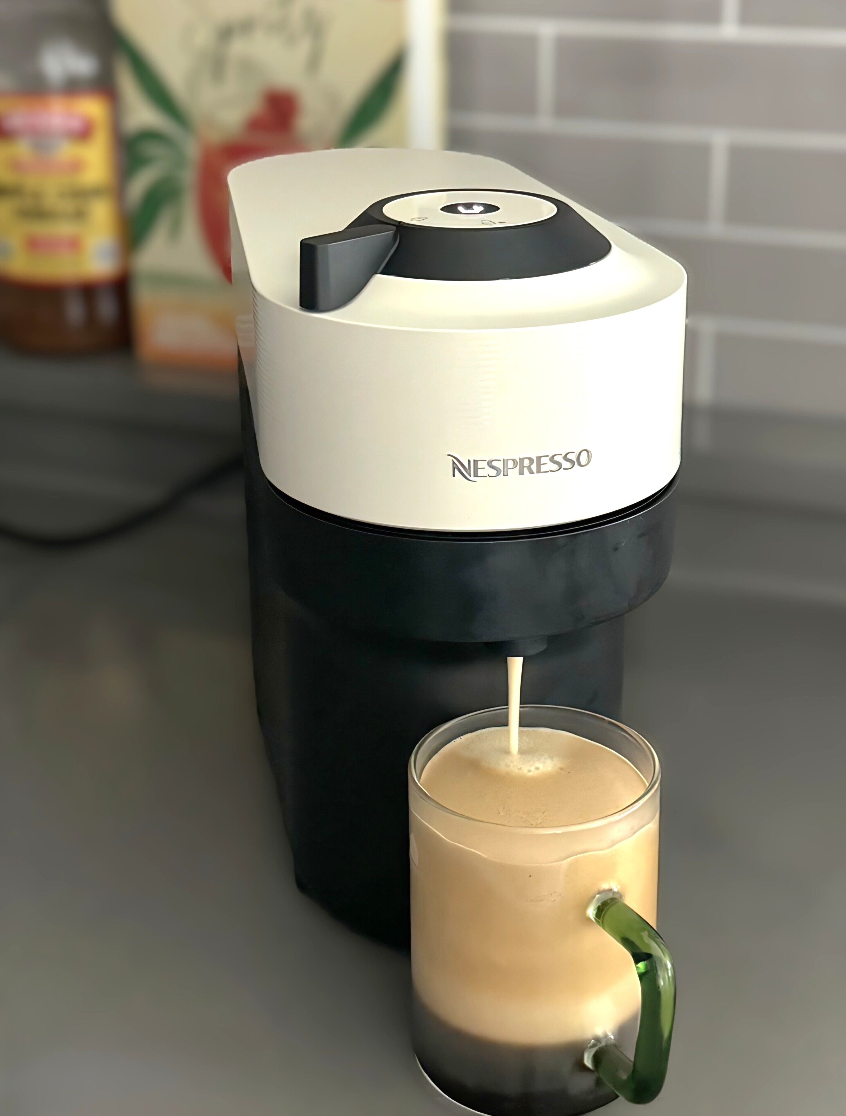 A Nespresso coffee machine dispensing coffee into a glass cup.