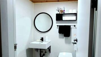 A small bathroom with a white sink, a toilet, and a mirror.