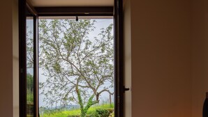 Ein Schlafzimmer mit großem Fenster, einem Bett und einer Nachttischlampe.