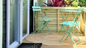 A wooden deck with a metal table and chairs, a sliding glass door, and a doormat with 'hello' on it. - Serene Modern Luxe king Suite~Minutes To Lido Beach, Downtown, UTC + Siesta Key (Sarasota)