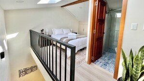 Ein Schlafzimmer mit Bett, Nachttischen, einer Holztür und einem Balkon mit Geländer.