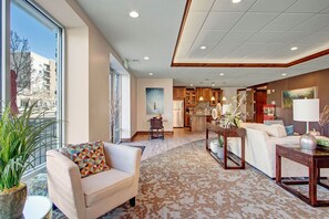 A spacious living area with a sofa, a coffee table, and a dining table. There is a kitchen in the background with wooden cabinets and a dining table. - Modern SLC Condo in Safe Area: Hot Tub & Mountain Access (Salt Lake City)