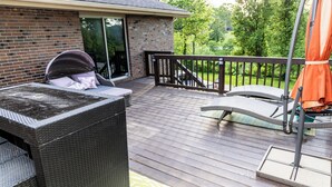Eine Terrasse mit Gartenmöbeln, eine Ziegelmauer und Blick ins Grüne.