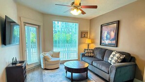 A living room with a sofa, armchair, coffee table, and a ceiling fan. - Chic & Modern 2BR Condo (Salt Lake City)
