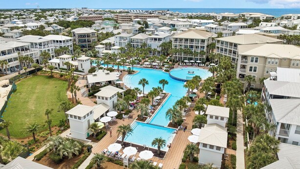 Un resort con piscina central, varias construcciones y palmeras.