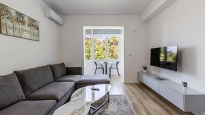 Una sala moderna con un sofá, una mesa de centro, un televisor y un comedor con sillas.
