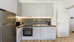 Una cocina moderna con horno empotrado, microondas y pileta, y piso de madera.