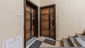 Un pasillo con dos puertas de madera, una pared blanca y una escalera.