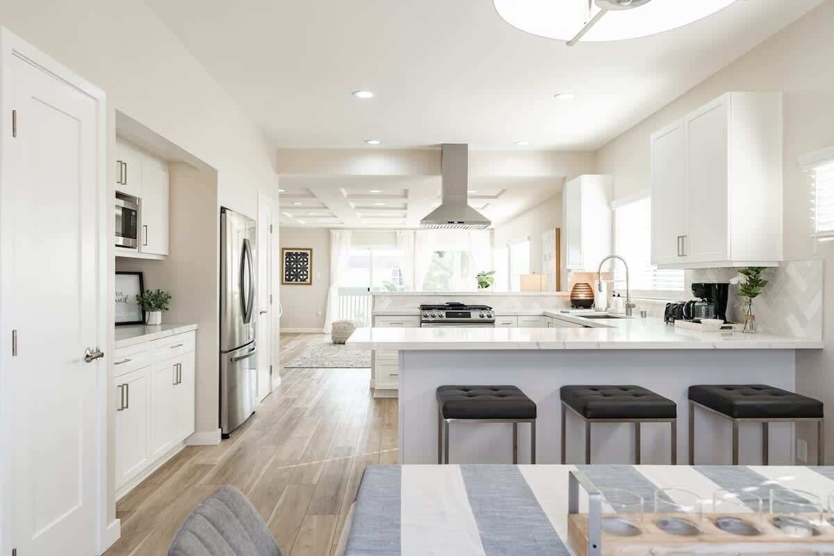 A modern kitchen with white cabinetry, stainless steel appliances, and a central island with stools.