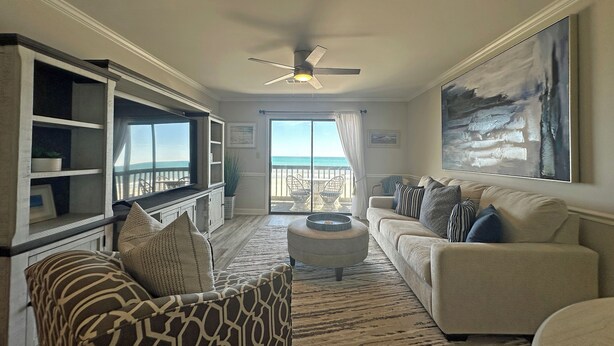 A living room with a view of the ocean, a ceiling fan, and a large painting. - Surfwatch II 204 - Oceanfront in Surfside Beach (Surfside Beach)