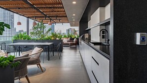 Eine moderne Küche mit schwarzem Arbeitsplatz, Spüle aus Edelstahl und einem eingebauten Backofen. Es gibt einen Essbereich mit Tisch und Stühlen sowie eine Sitzecke mit einer Couch und Kissen.