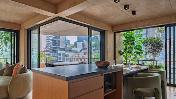 Una cocina moderna con un ventanal amplio, armarios de madera y un comedor con sillas.