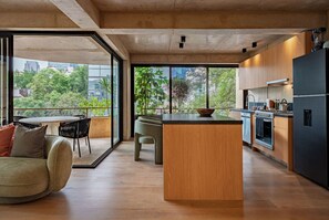Una cocina moderna con una isla central, ventanas amplias y una zona de comedor con sofá y sillas.