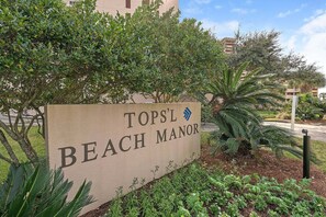 Schild für Topsl Beach Manor mit Blick auf die umliegende Bepflanzung und Gebäude.