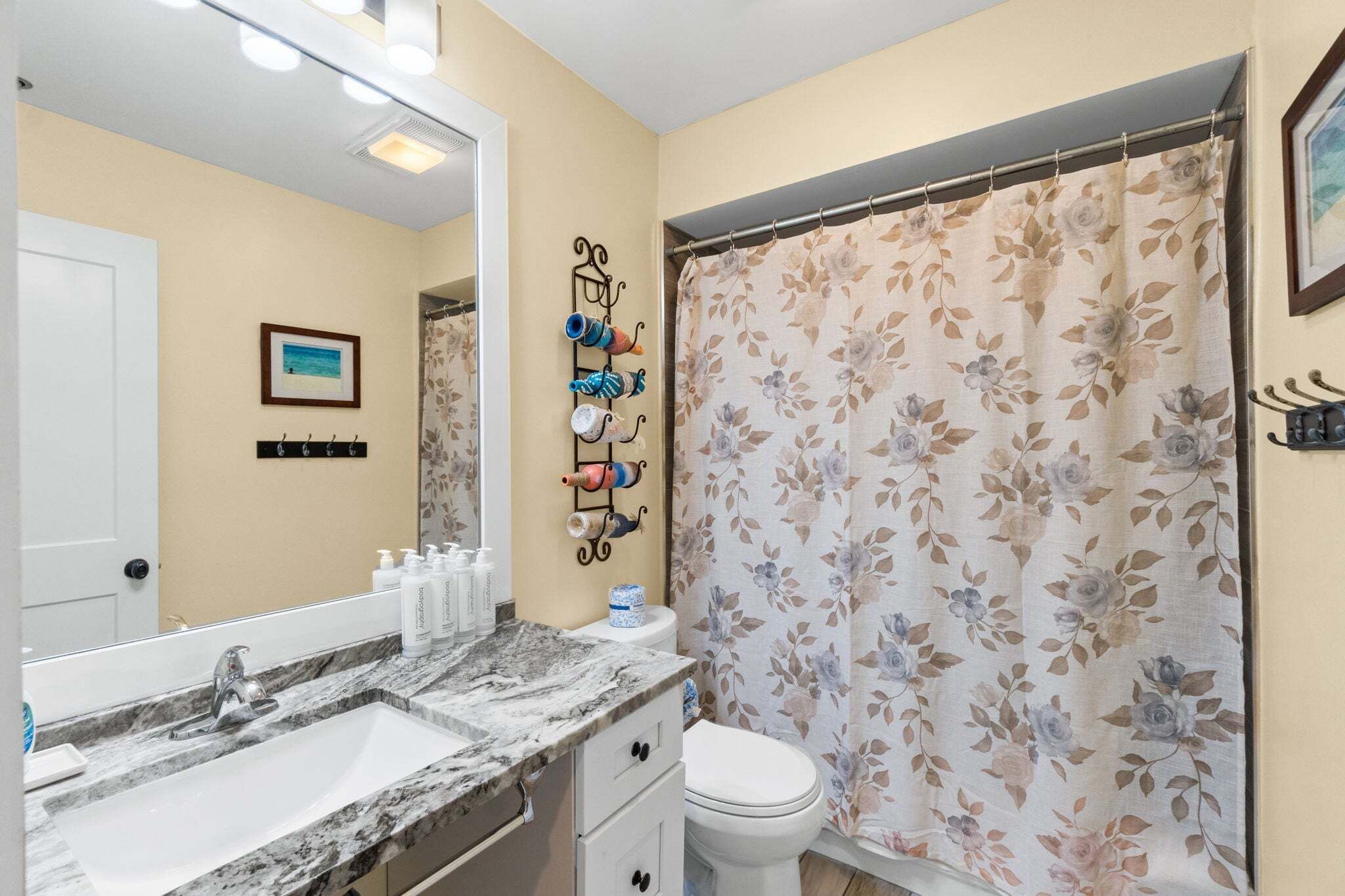 Une salle de bain équipée d’un lavabo, d’un miroir, de toilettes et d’un rideau de douche.