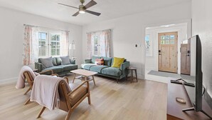 Un salón amplio con un sofá, sillones, una mesa de centro y una televisión.