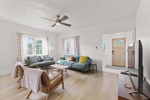 A spacious living room with a sofa, chairs, a coffee table, and a television.