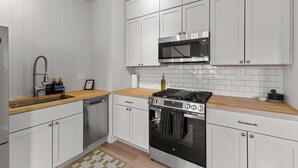 Una cocina moderna con gabinetes blancos, estufa de acero inoxidable y microondas.