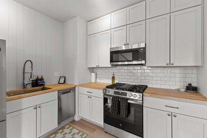 A modern kitchen with white cabinets, a stainless steel stove, and a microwave.