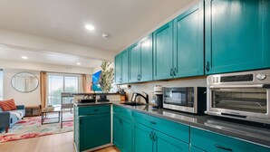 Une cuisine moderne avec des armoires de couleur turquoise, des appareils électroménagers en acier inoxydable et une grande fenêtre.