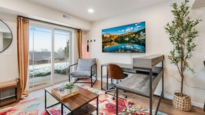 Une chambre moderne équipée d’un bureau, d’une chaise et d’une grande fenêtre donnant sur un paysage enneigé.