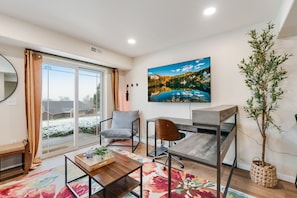 A modern room with a desk, chair, and a large window with a view of a snowy landscape. - 1BR Cozy Studio, Patio, Grill, Near Garden of Gods (Colorado Springs)