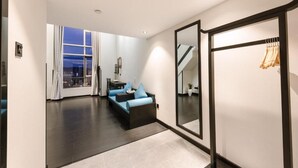 A modern hotel room with a large window, a sofa, a mirror, and a coat rack. - Gongxili - Yuejian Hotel (Kunming)