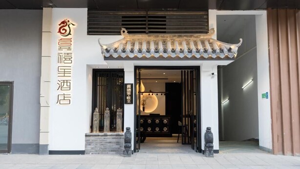 A hotel entrance with traditional Chinese architectural elements, a signboard, and a reception desk. - Gongxili - Yuejian Hotel (Kunming)