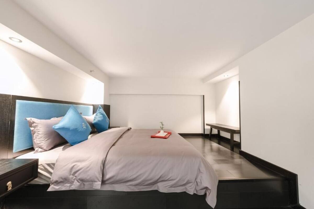 A modern bedroom with a large bed, a bedside table, and a bench along the wall.